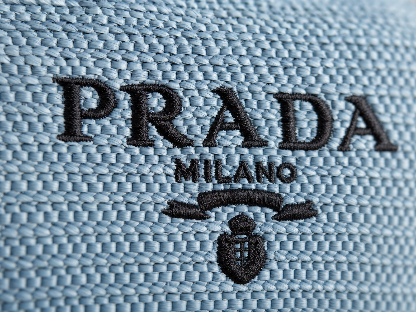 Close-up of embroidered PRADA MILANO logo on raffia